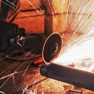 Image montrant quelqu'un découper un tuyau en métal à l'aide d'une disqueuse.